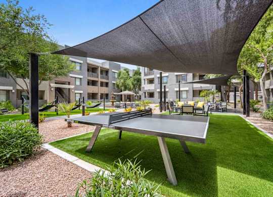 A ping pong table is in the middle of a grassy area.
