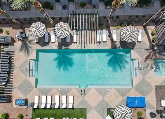 A large swimming pool surrounded by lounge chairs and umbrellas.