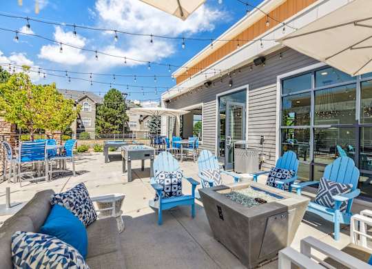 a patio with blue chairs and a fire pit