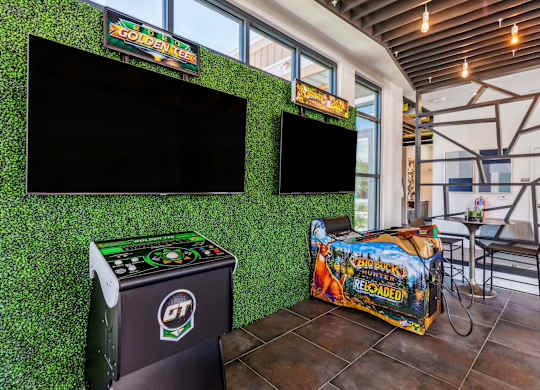 a game room with green astroturf and flat screen televisions