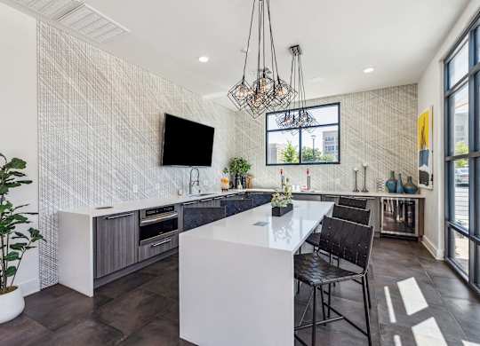a kitchen with a large white island with two stools and a chandelier