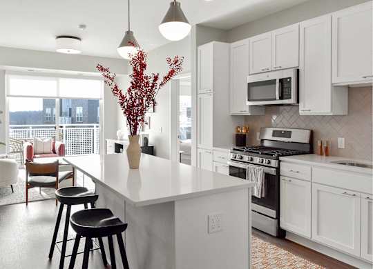 Bright kitchen with large white island and bar seating at The Hallon apartments for rent in Hopkins, Minnesota