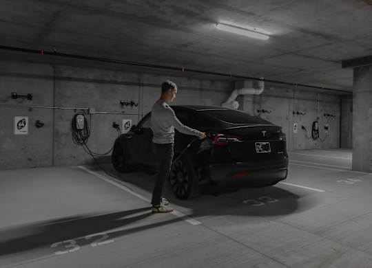 A man is charging an electric car in a parking garage.