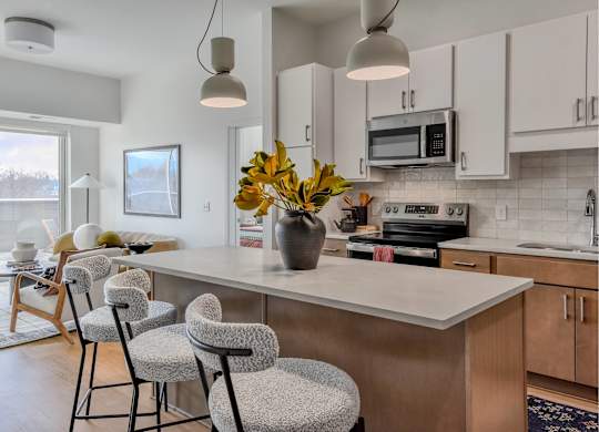 A kitchen with a white countertop and a vase of yellow flowers on it.