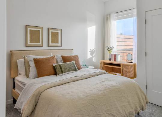 A bedroom with a large bed and two framed pictures on the wall.