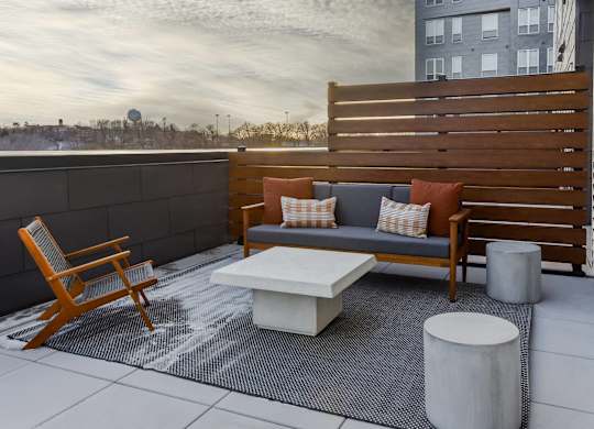 A wooden chair and a white table are on a patio.