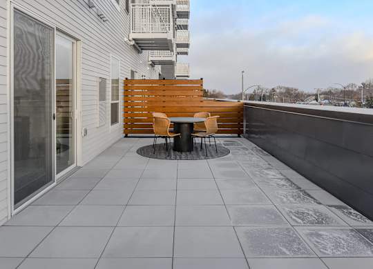 A patio with a table and chairs on a balcony.