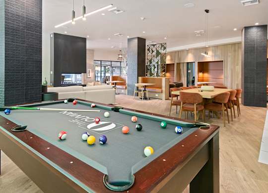 A pool table is in the middle of a room with a dining table and chairs.