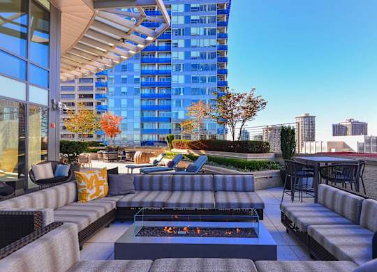 A patio with a fire pit and seating area with a view of a city skyline.