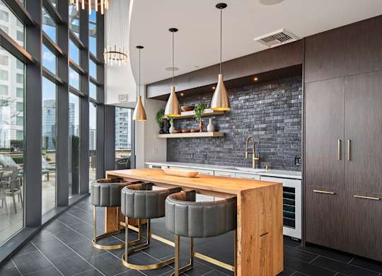 A modern kitchen with a wooden island and grey bar stools.