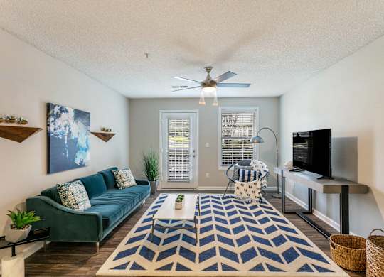 A living room with a blue couch and a rug.