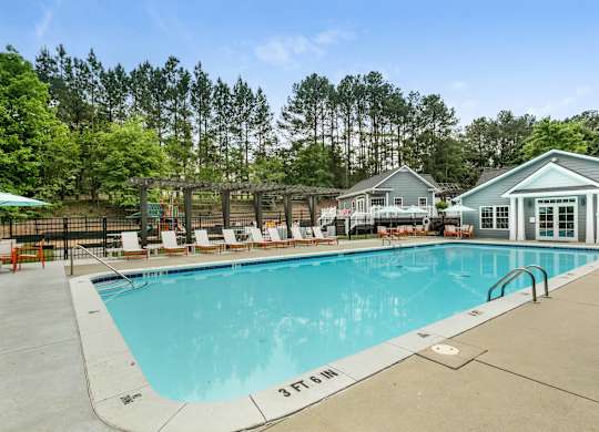 Pool next to line of tall trees at Aqua Sandy Springs apartments for rent in Sandy Springs, GA.