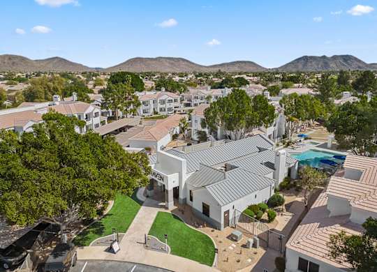 A large white building with a pool in the foreground and a mountain range in the background.