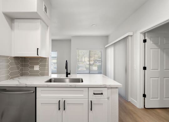 A modern kitchen with white cabinets and a marble countertop.