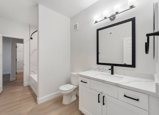 A bathroom with a toilet, sink, and mirror.