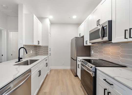 A modern kitchen with white cabinets and stainless steel appliances.