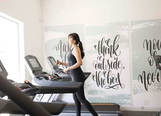 A woman is running on a treadmill in a gym.