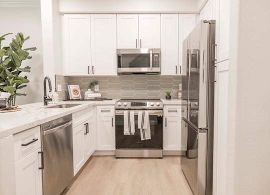 A modern kitchen with stainless steel appliances and white cabinets.