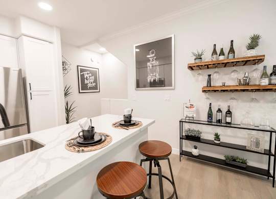A kitchen with a white marble countertop and a wooden stool.