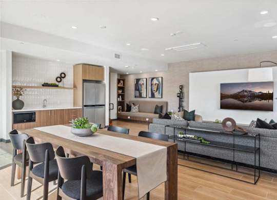 A modern living room with a wooden dining table and grey couch.