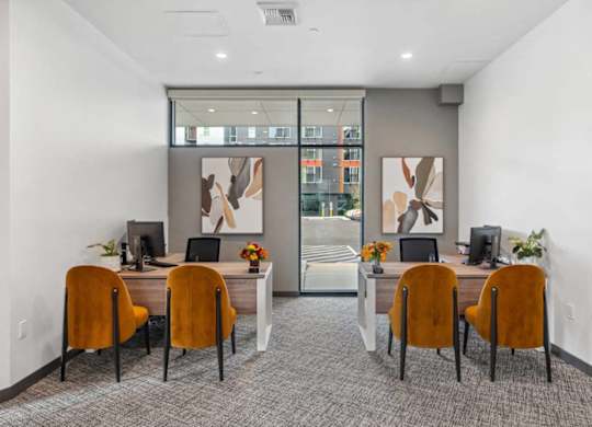 A room with a desk and chairs with a painting on the wall.