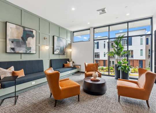 A modern living room with a grey sofa, orange chairs, and a coffee table.
