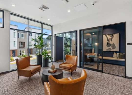 A modern living room with brown chairs and a glass door.