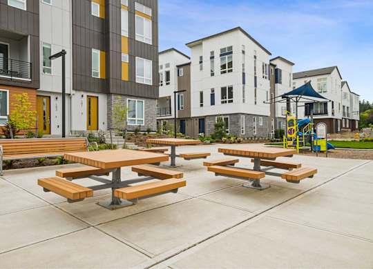 Picnic tables are set up in a courtyard between two buildings.