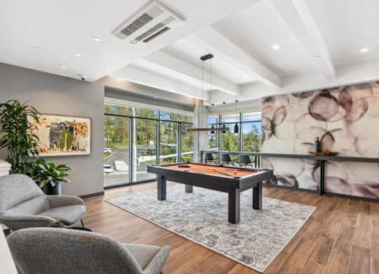 A modern living room with a pool table and a large painting on the wall.