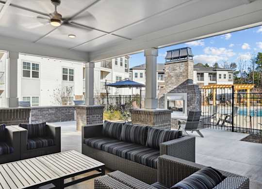 A patio with a black couch and a wooden table.