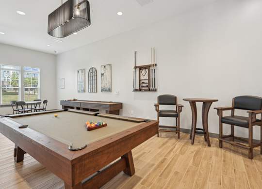 A pool table is surrounded by chairs in a room.