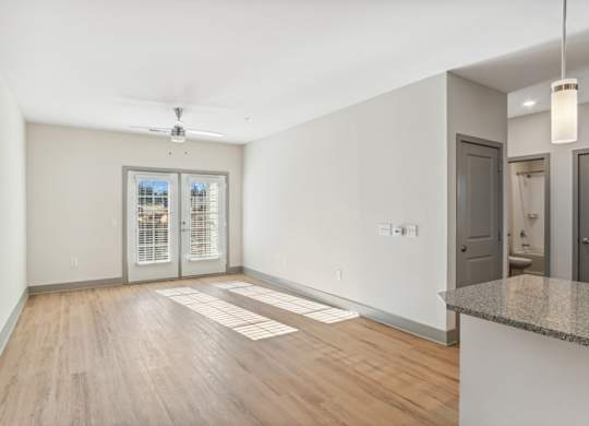 A spacious room with a ceiling fan and a window with blinds.