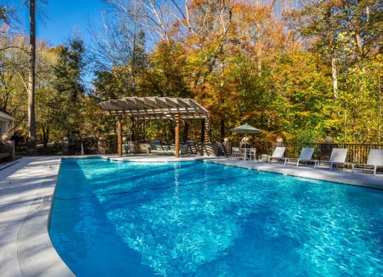 a swimming pool with a pergola and chairs