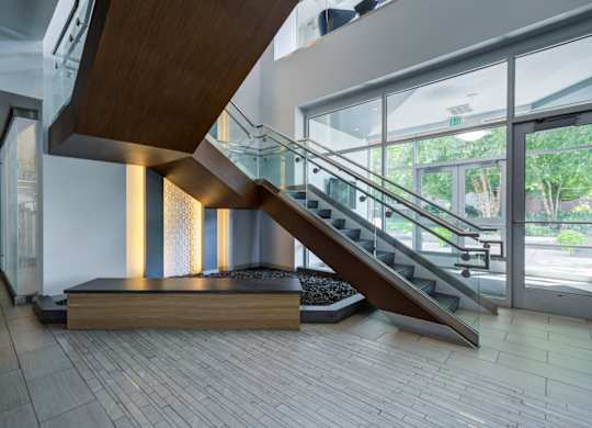 A staircase with a wooden handrail and a glass balustrade.