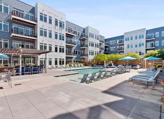 A sunny day at a poolside with apartment buildings in the background.