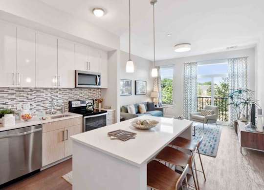 Model kitchen at RE150 Apartments in Medford, MA, featuring wood grain floor paneling and a kitchen island.