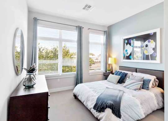 A bedroom with a large bed and a window with blinds.