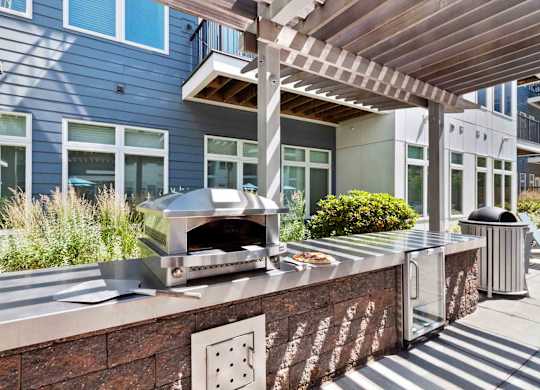 A modern outdoor kitchen with a pizza oven and a trash can.