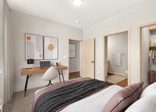 A bedroom with a bed, desk, and mirror.