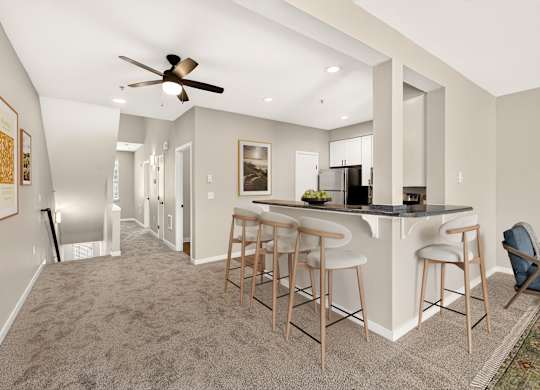 A spacious kitchen and bar area with a ceiling fan and lighting.
