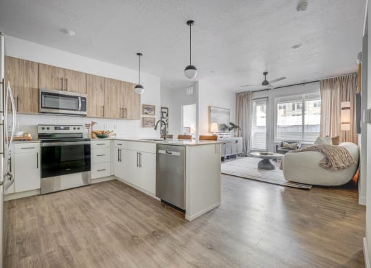 an open kitchen and living room with white cabinets and stainless steel appliances