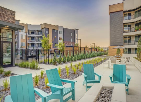 an outdoor patio with blue chairs and tables in front of an apartment building
