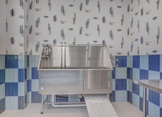 a large stainless steel sink in a kitchen with blue and white tiles