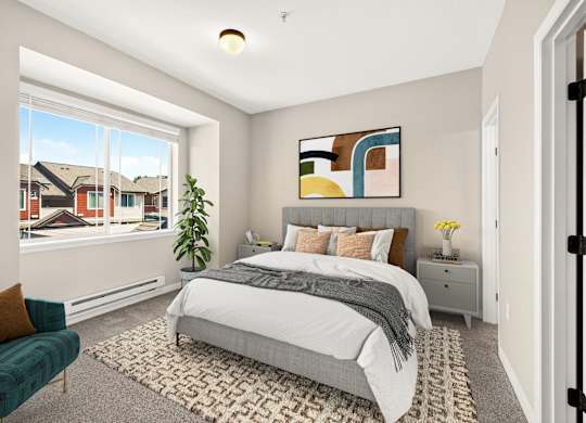 A bedroom with a large bed, a green chair, and a painting on the wall.