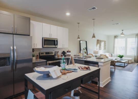 a kitchen with a large island and a living room in the background