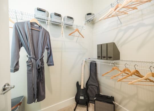 a walk in closet with a guitar and hangers