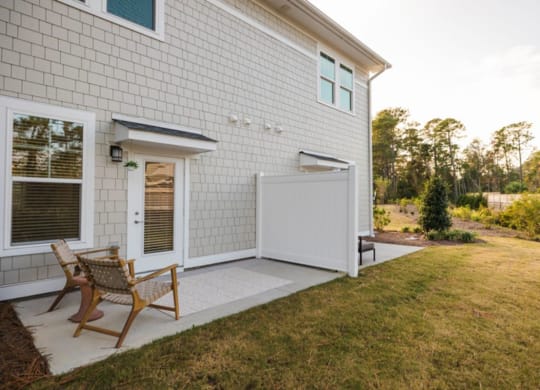 a white house with a white fence and a white patio with two chairs and a table