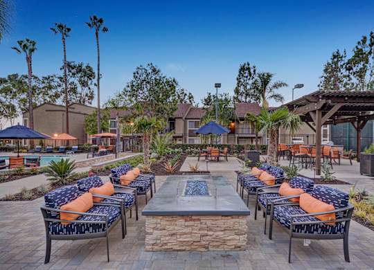 A patio with a fire pit surrounded by chairs and tables.