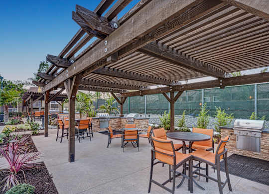 A patio with tables and chairs under a wooden pergola.