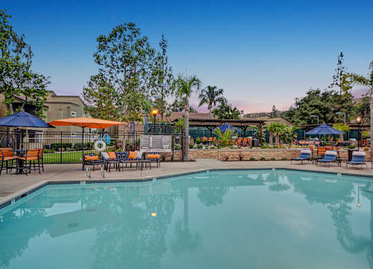 A large swimming pool surrounded by lounge chairs and umbrellas.